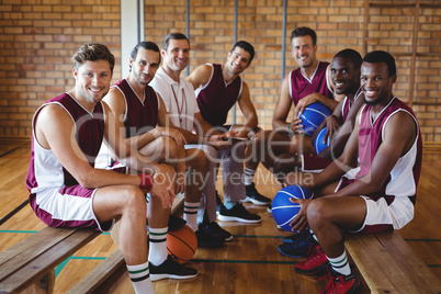 Smiling coach and basketball player sitting on bench