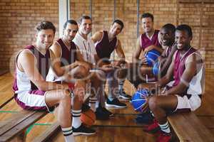 Smiling coach and basketball player sitting on bench