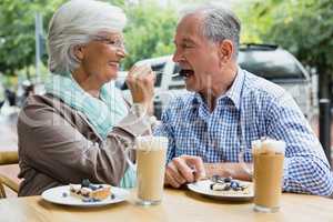 Senior woman feeding tart to man in cafÃ?Â©