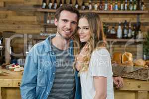 Portrait of smiling couple standing behind the counter