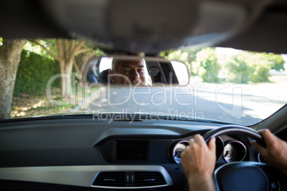 Reflection of senior man on mirror in car