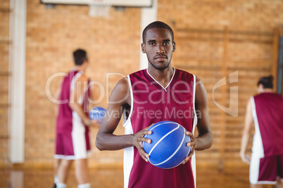 Confident  basketball player holding a basketball