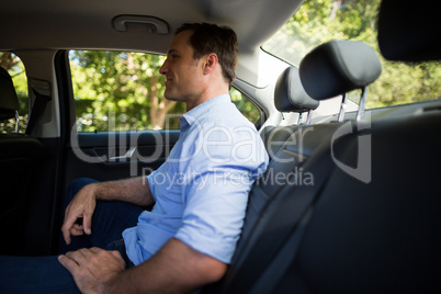 Young man sitting on back seat in car