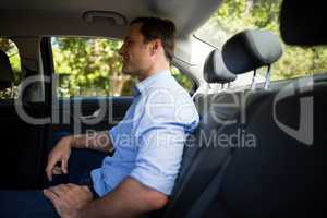 Young man sitting on back seat in car