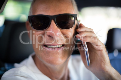 Portrait of senior man talking on phone in car