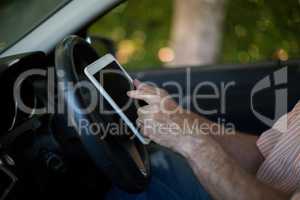 Senior man using digital tablet in car