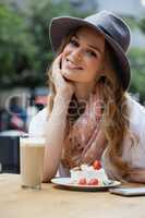 Smiling woman sitting by food at table in cafe shop