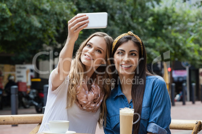 Happy friends photographing while sitting at cafe