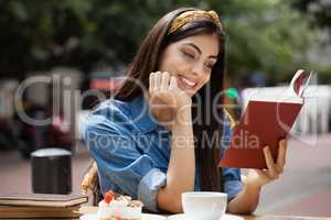 Woman reading book while sitting on chair at cafe shop