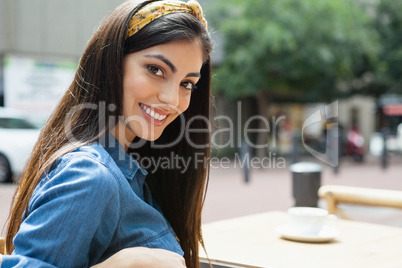 Portrait of beautiful woman sitting on chair at sidewalk cafe