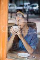 Thoughtful woman drinking coffee in cafe shop