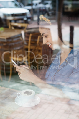 Woman using mobile phone while sitting at cafe shop