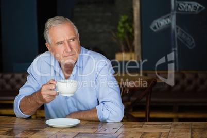 Thoughtful senior man holding coffee cup