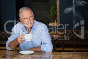 Thoughtful senior man holding coffee cup