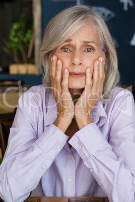 Portrait of worried senior woman at table