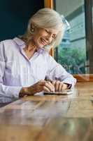 Smiling senior woman using smart phone while sitting at table
