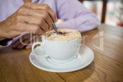 Close up of woman stirring coffee while sitting at table
