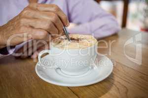 Close up of woman stirring coffee while sitting at table