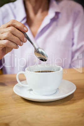 Cropped image of woman stirring coffee