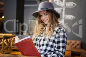 Portrait of woman wearing hat reading book