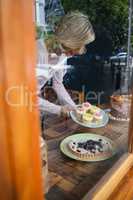 High angle view of senior woman holding cupcakes in plate
