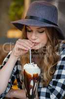 Young woman wearing hat drinking cold coffee