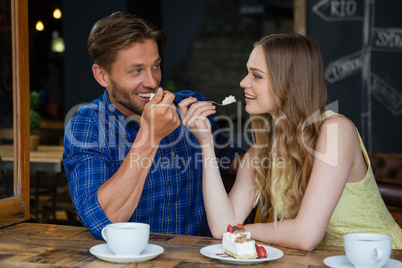 Happy couple eating sweet food while siitting at table