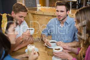 Friends interacting while having coffee at table