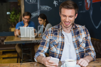 Man using mobile phone while having coffee