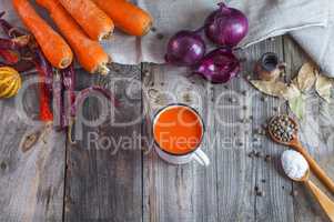 Fresh carrot juice in an iron mug on a gray wooden surface