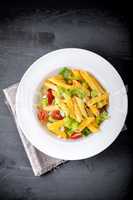 Pasta salad with fresh greenery and tomatos.