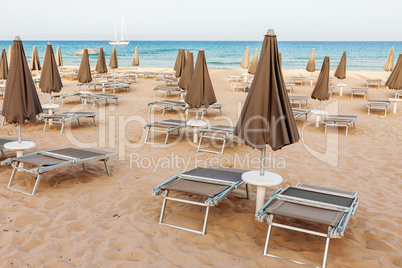 Empty beach with loungers and closed parasols