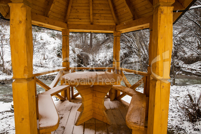 Snow covered wooden arbor .