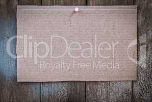 Piece of brown kraft paper hanging on a wooden wall