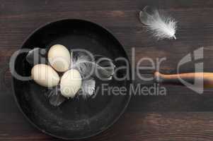 Three raw chicken eggs in a black cast-iron frying pan