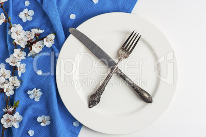 Crossed knife and fork on an empty white plate