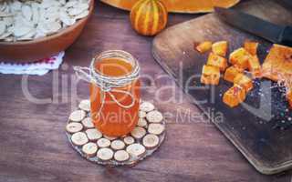 Pumpkin juice in a glass jar on a brown table