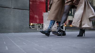 Happy women walking city street with shopping bags