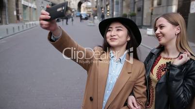 Happy women taking selfie after shopping on phone