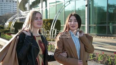 Happy women with shopping bags walking on street