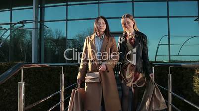 Happy women coming out of shopping mall with bags