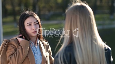 Cheerful asian girl gossiping with female friend
