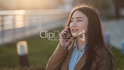 Positive young asian woman talking on mobile phone