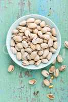 Pistachio nuts on wooden background, top view
