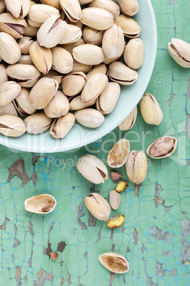 Pistachio nuts on wooden background, top view