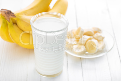 Yogurt with fresh bananas on white wooden background closeup, healthy breakfast