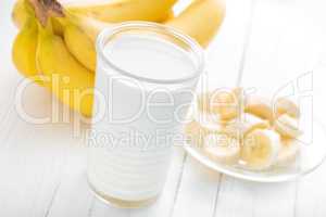 Yogurt with fresh bananas on white wooden background closeup, healthy breakfast