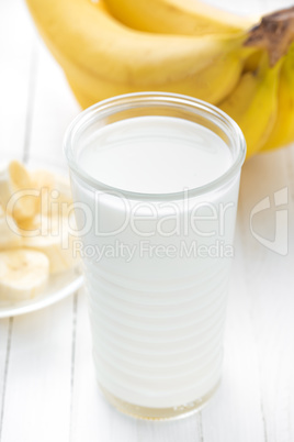 Yogurt with fresh bananas on white wooden background closeup, healthy breakfast