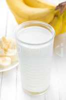 Yogurt with fresh bananas on white wooden background closeup, healthy breakfast