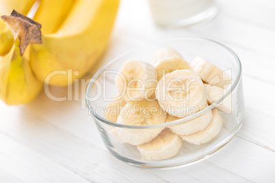 Fresh sliced bananas on white wooden background closeup, healthy eating